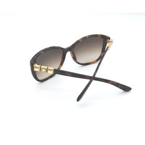 May include: Tortoiseshell sunglasses with gold accents on the arms. The lenses are brown.