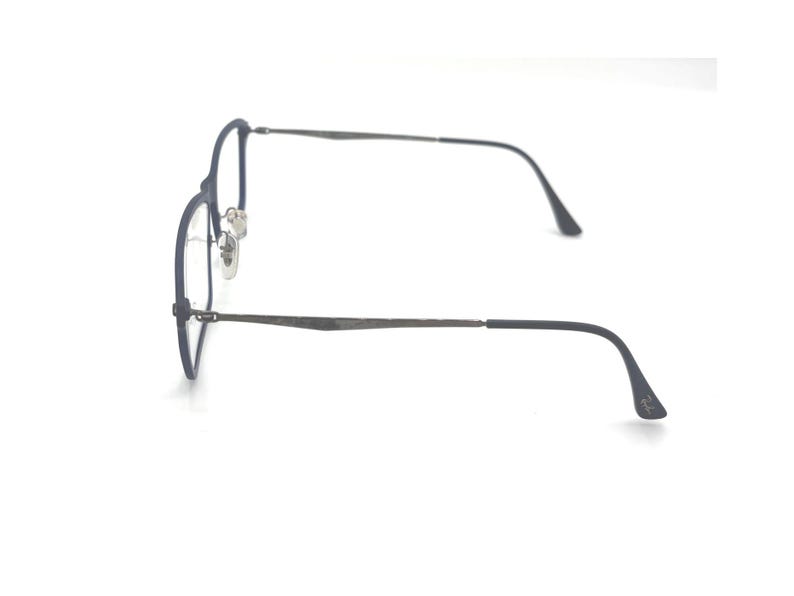 May include: A pair of eyeglasses with a dark blue frame and silver-colored lenses. The glasses have a thin, round frame design and curved temples. The image is taken against a white background, highlighting the sleek design of the eyewear.