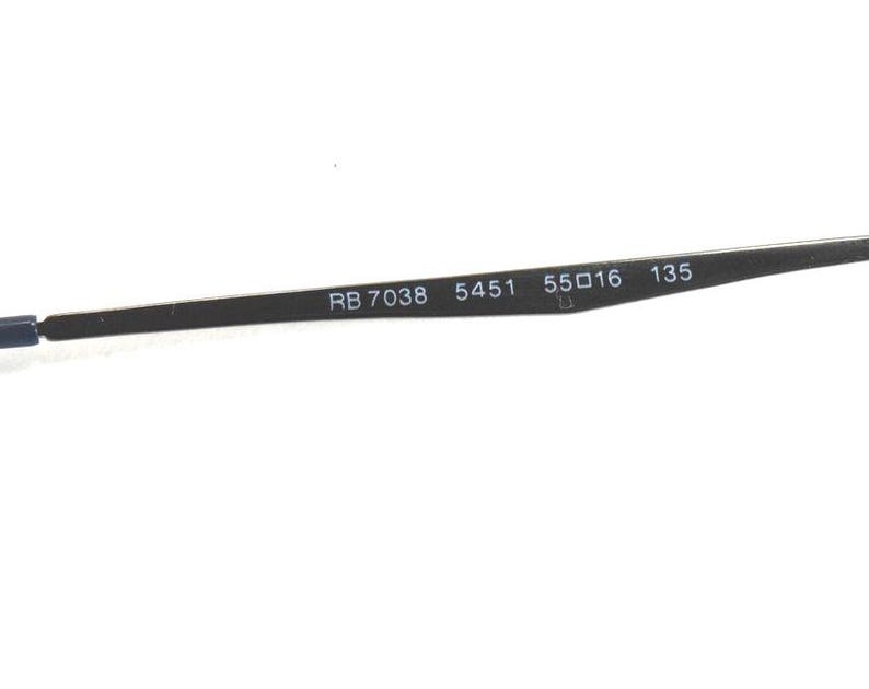 May include: Close-up of a black eyeglass arm with the text "RB 7038 5451 55O16 135". The arm is thin and metallic, with the numbers and letters printed in white.
