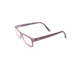 K&ouml;nnte beinhalten: Rechteckige Brille in Lila und Braun mit dem Ray-Ban-Logo an der Seite.