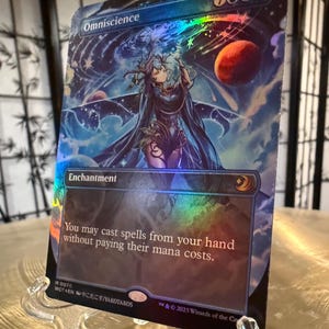 May include: A blue and silver Magic: The Gathering card with the text "Omniscience" and "You may cast spells from your hand without paying their mana costs." The card features a woman with long blue hair and a blue dress standing in front of a starry sky.