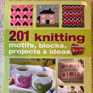 May include: A book titled "201 Knitting Motifs, Blocks, Projects & Ideas" by Nicki Trench. The cover features colorful knitted designs, including hearts, houses, and geometric patterns. The book also shows examples of knitted projects, such as mug cozies, a pillow, and bee ornaments.