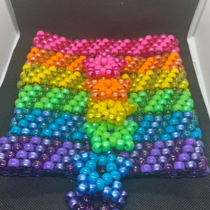 May include: A rainbow-colored beaded keychain with a star-shaped design. The keychain is made of small, colorful beads that are strung together in a pattern. The keychain is a fun and colorful accessory that can be used to add a touch of personality to any bag or key chain.