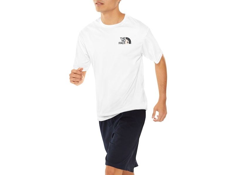 May include: A white short-sleeved t-shirt with a black and white logo that says "THE NORTH FACE" on the front. The person is wearing navy blue shorts.