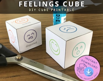 Könnte beinhalten: Zwei weiße Papierwürfel mit verschiedenen Emotionen bedruckt. Ein Würfel zeigt "Angst", "wütend" und "angeekelt". Der andere Würfel zeigt "traurige" und "glückliche" Gesichter. Der Text "FEELINGS CUBE DIY CUBE PRINTABLE" steht oben.