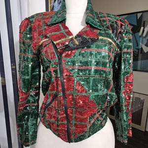 May include: A green and red sequined jacket with a zipper closure. The jacket has a geometric pattern and gold accents.