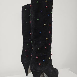May include: Black suede knee-high boots with a stiletto heel and colorful embroidered dots.