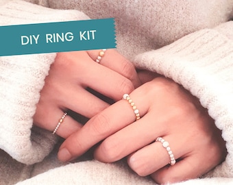 May include: DIY Ring Kit with three different rings made of gold and silver beads. The rings are on a person's hand.