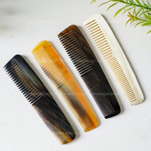 May include: Four combs made of natural horn. The combs are in various shades of brown, black, and white. The combs have fine teeth and are designed for detangling and styling hair.