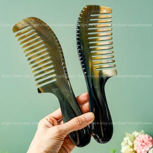 May include: Two brown and black horn combs with a curved handle. The combs have a fine tooth design.