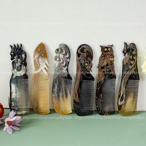 May include: Six decorative combs with carved animal designs. The combs feature intricate carvings of a bird, fish, and owls. The combs are in shades of brown, black, and tan, with yellow accents. The combs are displayed on a light green surface.