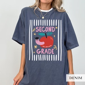 Pu&ograve; includere: T-shirt color denim con grafica per la seconda elementare. Il design presenta una mela con un verme, stelle e le parole "SECOND GRADE" e "MRS. WILLIAMS". La maglietta ha una vestibilit&agrave; comoda e oversize.