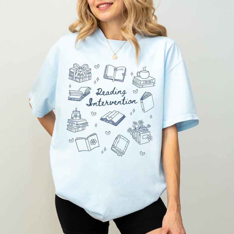 May include: Light blue t-shirt with a graphic design of books, hearts, and the text "Reading Intervention".