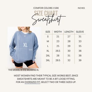 May include: Size chart for a sweatshirt in inches. The chart shows the width, length, and sleeve length for sizes S, M, L, XL, 2XL, and 3XL. The model is wearing a size XL.