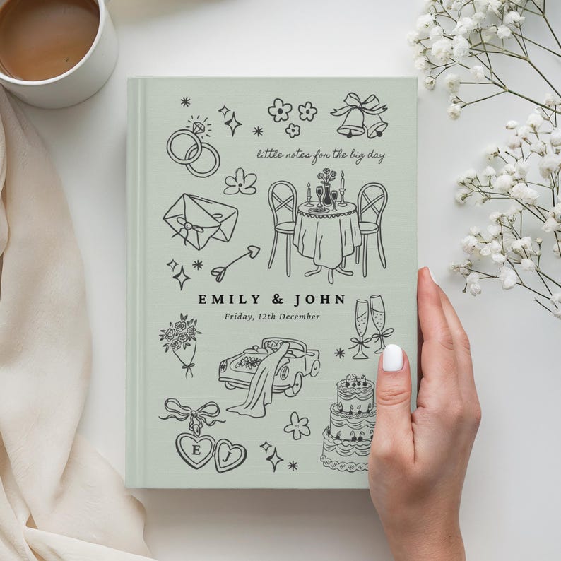 May include: A sage green hardcover notebook featuring black line art illustrations of wedding-themed icons, including rings, a car, a cake, and champagne flutes. The text reads "little notes for the big day", "EMILY & JOHN", and "Friday, 12th December".
