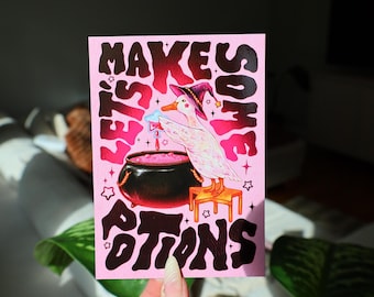 May include: A rectangular art print on a light pink background featuring a white duck wearing a purple witch hat, standing on an orange stool next to a black cauldron filled with pink liquid. The text reads LET'S MAKE SOME POTIONS in black.