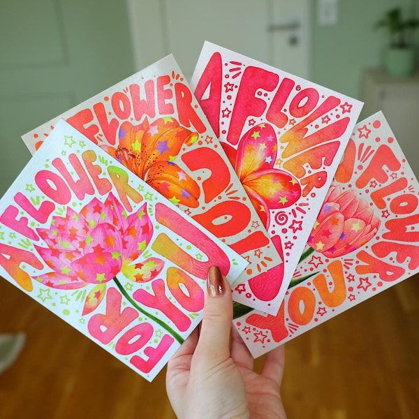Puede incluir: Tres tarjetas de felicitación rectangulares con ilustraciones florales en tonos vibrantes rosa, naranja y amarillo. Cada tarjeta muestra el texto A FLOWER FOR YOU en rosa y naranja intenso, decorado con pequeñas estrellas verdes y amarillas.