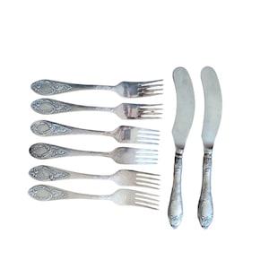 May include: Set of six silver forks and two silver butter knives with ornate handles.