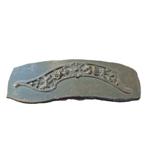 May include: A dark green, cast iron, decorative piece with a floral design. The piece is curved and has a raised design of flowers and leaves.