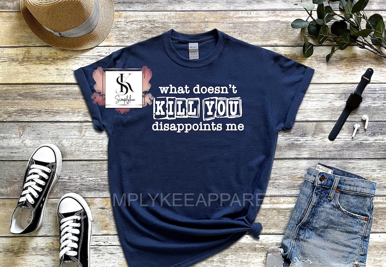 May include: A navy blue t-shirt with white text that reads "what doesn't kill you disappoints me". The text is in a blocky font and appears to be printed on a distressed fabric.