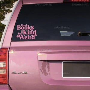 May include: A pink car with a window decal that reads "Read Books Stay Kind Weird" in a stylized font. The decal is in a cursive font. The car has a 4x4 emblem.