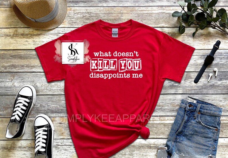 May include: Red t-shirt with white text that reads "what doesn't kill you disappoints me". The text is in a blocky font and appears to be printed on the shirt.