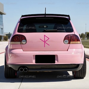 May include: A pink car with a black spoiler and a pink symbol on the back. The car has black tires and dual exhaust pipes. The text "SIMPLYKEE APPAREL" is printed on the car.