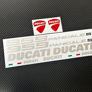 Peut inclure: Ensemble d'autocollants Ducati avec le logo Ducati rouge et blanc, ainsi que le texte argenté "959 Panigale S" et "Ducati". Les autocollants incluent des bandes aux couleurs du drapeau italien.