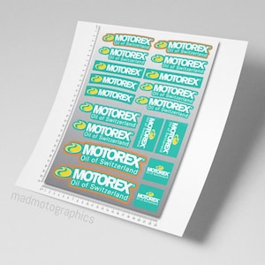 Peut inclure: Une feuille d'autocollants avec le logo "MOTOREX Oil of Switzerland". Les autocollants sont bleu turquoise avec un logo jaune et blanc. La feuille est imprimée sur du papier blanc.