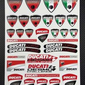 May include: A sheet of stickers featuring the Ducati Corse logo in various colors and designs. The stickers include the words "Ducati Corse", "Ducati Desmo Challenge", and "Ducati Performance".