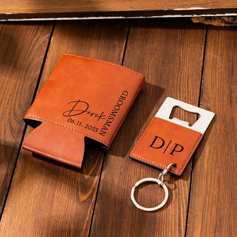 May include: A brown leather groomsman gift set with a personalized can cooler and a bottle opener keychain. The can cooler has the name "Derek" and the date "06.11.2025" engraved on it. The bottle opener keychain has the initials "D/P" engraved on it.