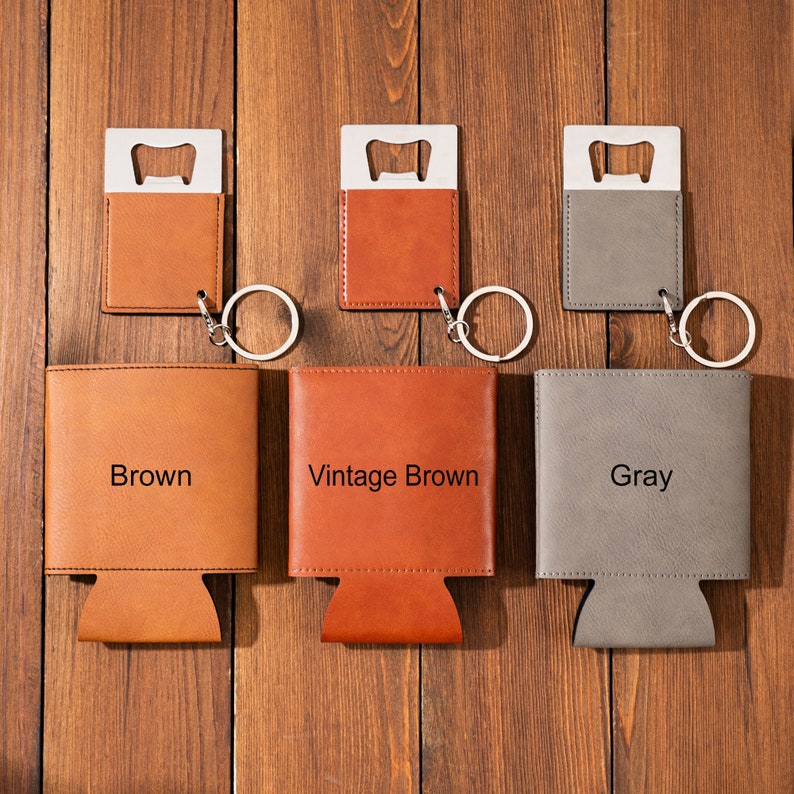 May include: Three leather can coolers with bottle opener keychains. The coolers are brown, vintage brown, and gray. Each cooler has the color name printed on the front.