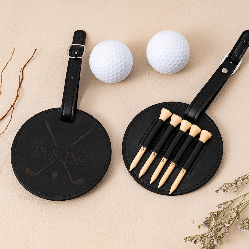 May include: Black leather golf bag tag with a personalized name "DURLING" and crossed golf clubs. The tag has a loop for attaching to a bag and comes with six golf tees.