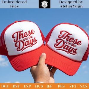 Puede incluir: Dos gorras de camionero rojas y blancas con la frase bordada "These are the Days". Las gorras tienen una parte trasera de malla y una visera curva. También se ve el texto "Embroidered Files" y "Designed by AtelierYujin".