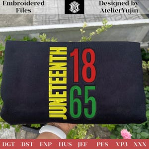 May include: Black fabric with embroidered text and numbers. The word "JUNETEENTH" is vertically embroidered in yellow, with the numbers "18" in red and "65" in green. The design is by AtelierYujin.
