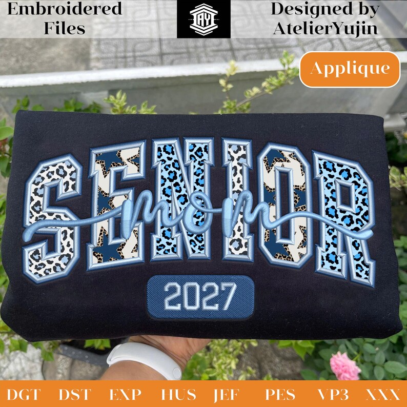 May include: Black sweatshirt with the words "SENIOR mom 2027" embroidered in blue and leopard print. The design includes the text "Embroidered Files" and "Designed by AtelierYujin". The word "Applique" is also visible.