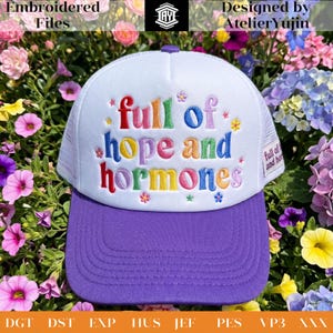 Könnte beinhalten: Eine weiße Trucker-Mütze mit lila Schirm und weißem Mesh-Rücken. Die Mütze hat den gestickten Schriftzug "full of hope and hormones" in bunten Buchstaben. Die Mütze ist von bunten Blumen umgeben.