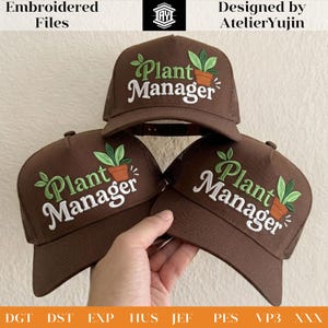 以下が含まれることがあります： 白い文字と緑色の植物ポットのグラフィックで「Plant Manager」と刺繍された茶色のトラッカーハット。AtelierYujinのデザインで、刺繍ファイルです。