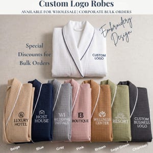 May include: A collection of waffle-weave robes in beige, blue, gray, pink, brown, sage green, and charcoal, each featuring embroidered text and logos. The robes are displayed with a white robe at the top, labeled with Custom Logo and Embroidery Design.