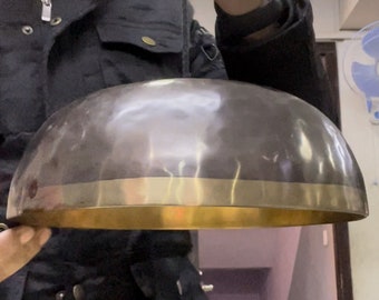 Op de afbeelding: Een grote, ronde, zilveren zangkom met een gouden rand. De kom wordt vastgehouden door een hand.