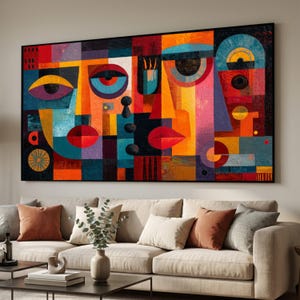 Puede incluir: Obra de arte abstracta que representa un rostro compuesto por formas geométricas en una paleta de colores vibrantes. La pintura utiliza rojo, naranja, azul y amarillo, enmarcada en negro. Cuelga sobre un sofá beige con cojines.