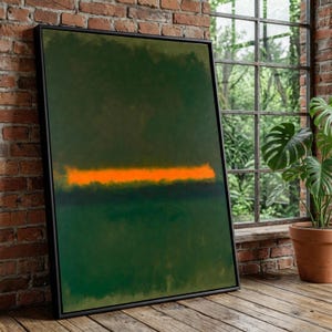 May include: Abstract art print in a black frame. The artwork features a dark green background with an orange horizontal stripe. The framed art is leaning against a brick wall next to a window.