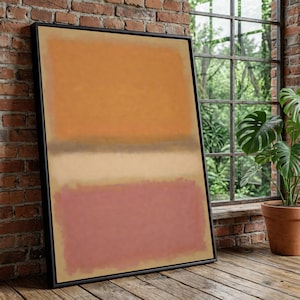Könnte beinhalten: Abstrakter Kunstdruck in einem schwarzen Rahmen. Das Kunstwerk zeigt drei horizontale Farbblöcke: einen oberen Abschnitt in Orange, einen mittleren Abschnitt in Beige und einen unteren Abschnitt in Rosa. Die gerahmte Kunst lehnt an einer Backsteinmauer.