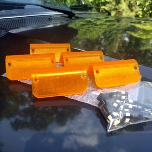 May include: Four orange plastic automotive light covers and a bag of white LED light bulbs.