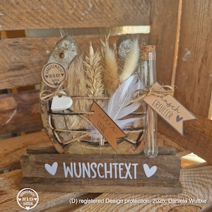 Op de afbeelding: Een decoratief hoefijzer op een houten voet met de tekst WUNSCHTEXT. Het bevat gedroogde tarwe, witte veren, een glazen buisje en bruine papieren labels met de tekst DU & ICH, alles LIEBE en WUNSCH ERFÜLLER bevestigd met een touwtje.