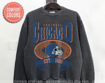 May include: A dark gray sweatshirt with a vintage-style graphic of a football helmet and the text "FOOTBALL CHICAGO EST. 1920".