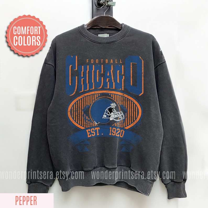 May include: A dark gray sweatshirt with a vintage-style graphic of a football helmet and the text "FOOTBALL CHICAGO EST. 1920".