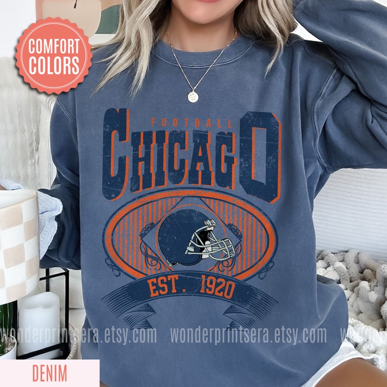 May include: A blue sweatshirt with a vintage-style graphic of a football helmet and the text "FOOTBALL CHICAGO EST. 1920".