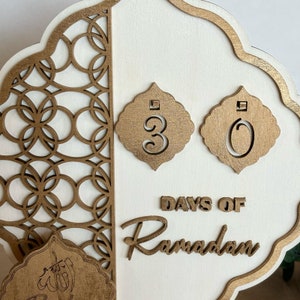 Pu&ograve; includere: Un cartello in legno bianco con un design intricato dipinto in oro. Il cartello dice "30 giorni di Ramadan" in lettere dorate. Il cartello &egrave; perfetto per contare i giorni del Ramadan.