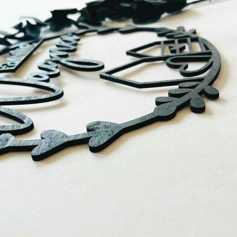 May include: Black wooden sign with the words "Our Forever" and a house design. The sign is decorated with a leafy wreath.